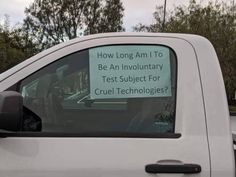 a white truck with a sign on it's side window that says how long am i to be an involutory test subject for cruel technologies?