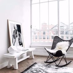 a rocking chair in front of a window with a white rug on the floor next to it