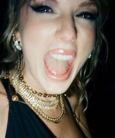 a close up of a person wearing jewelry and making a face with her mouth open