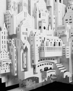 a black and white photo of a city made out of cut outs with buildings in the background