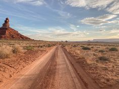 a dirt road in the middle of an arid area with rocks and grass on both sides