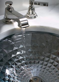 a chrome faucet with water running from it's spout into the sink