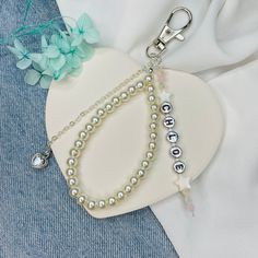 a white heart shaped plate with two bracelets and a keychain on it