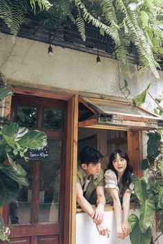 a man and woman sitting in the window of a building