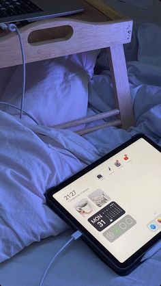 an apple laptop computer sitting on top of a bed next to a wooden desk and chair