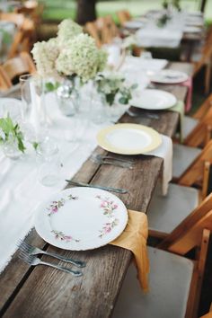 a long table with plates and flowers on it