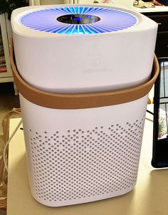 an air purifier sitting on top of a table next to a cell phone