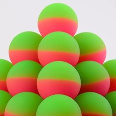 a pile of green and red balls sitting on top of each other in front of a white background