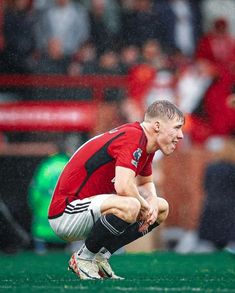 a soccer player crouches on the field in the rain as he waits for his team's next play