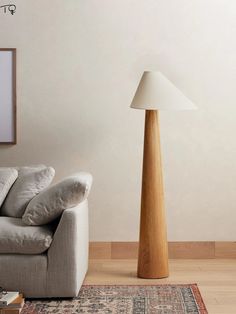 a living room with a white couch and wooden floor lamp next to a rug on the floor