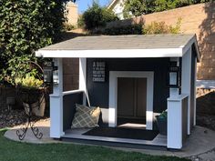 a black and white dog house sitting on top of a grass covered yard next to a tree