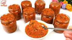 a person is spooning some food out of a small bowl with several jars in front of them