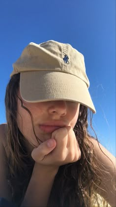 a girl wearing a hat with her hand under her chin