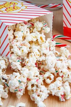 some popcorn is sitting on a table next to two boxes with candy canes in them