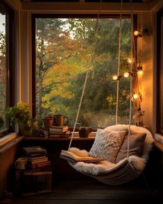 a hanging chair in front of a window with a book and some lights on it