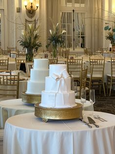 three tiered wedding cake sitting on top of a table in a banquet room with white linens