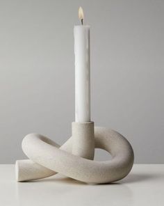 a white candle sitting on top of a table next to an object that looks like a knot