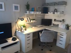 a white desk topped with a computer monitor next to a chair and shelves filled with books