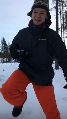 a young boy in an orange pants and black jacket is playing with a frisbee