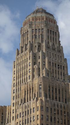 the top of a tall building with many windows on it's sides and a sky background