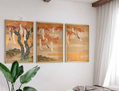 three paintings hang on the wall above a bed