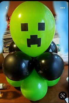 a green balloon sitting on top of a wooden table next to black and white balloons