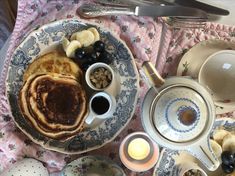 a table topped with plates and cups filled with breakfast foods next to utensils