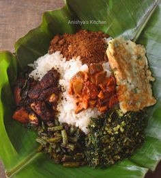 a green plate with rice, meat and other foods on it is sitting on a wooden table