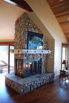 a living room with a stone fireplace and wood floors