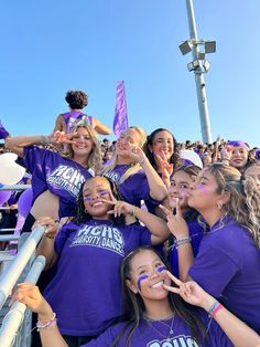 a group of girls in purple shirts standing next to each other at a football game