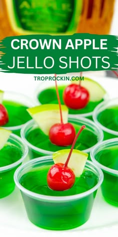 small cups filled with green jello shots and cherries on the rims are topped with pineapple slices