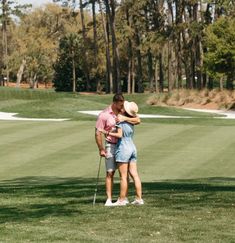 two people hugging each other on a golf course