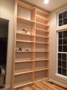 an empty bookcase in the corner of a room with wood flooring and windows