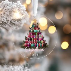 a christmas ornament hanging from a tree with lights in the background and an ornament that says saphlea