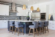 a large kitchen with an island and bar stools in the center, surrounded by white cabinets