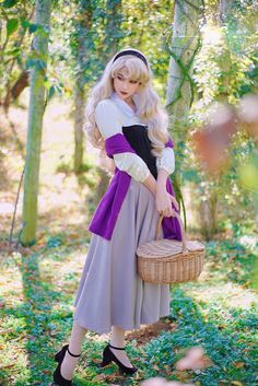 a woman in a dress holding a basket and posing for the camera with trees behind her