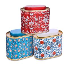 three tins with different designs on them sitting next to each other in front of a white background