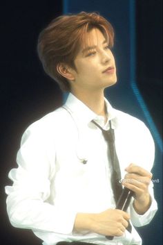 a young man in white shirt and tie holding a microphone