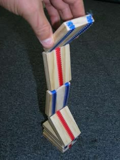 a hand is holding two wooden blocks with red, white and blue ribbons on them