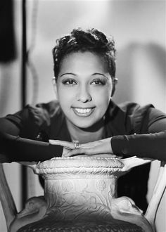 a black and white photo of a woman leaning on a vase