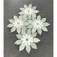 some white flowers sitting on top of a black stone floor next to a tile wall