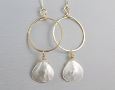 "Beautiful and elegant! These Mother of Pearl Hoop Earrings are to be your favorite go-to jewelry. Medium sized handcrafted hoops are slightly hammered. Lustered fan-shaped natural white Mother of Pearls are attached to the hoops. Dainty, simple with a boho feel earrings are perfect for day and night with the right amount of sparkle. These Shell Earrings are great for your wedding: the bride and bridesmaids. Earrings are measuring at 2 3/4\" long Hoop is 1\" Mother of Pearl Shells are 16 x 16mm Sea Shell Earrings, Double Horn Necklace, Pearl Earrings Gold, Bridesmaids Earrings, Earrings Gold Hoop, Long Chain Earrings, Mother Of Pearl Jewelry, Mother Of Pearl Earrings, Big Pearl