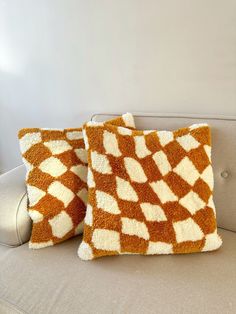 two orange and white pillows sitting on top of a couch