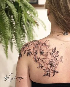 the back of a woman's shoulder with a cat and flowers tattoo on it