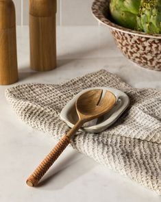 a wooden spoon sitting on top of a white plate next to a bowl filled with broccoli