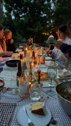 a group of people sitting around a table with food and drinks in front of them