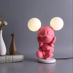 a pink figurine sitting on top of a table next to two vases