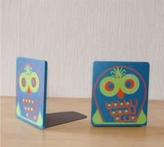 two small boxes with colorful designs on them sitting on a wooden table next to each other