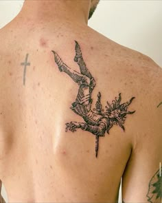 a man with a tattoo on his back holding a knife in one hand and pointing at the cross