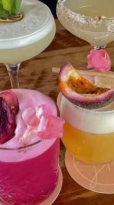 three different types of cocktails on plates with flowers in the middle and one has a piece of fruit